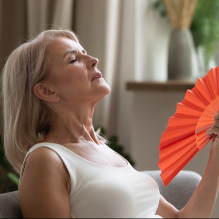 Sweaty older lady using paper waving fan