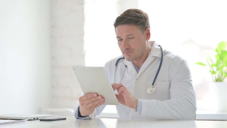 Male Doctor using Tablet while Sitting in Office