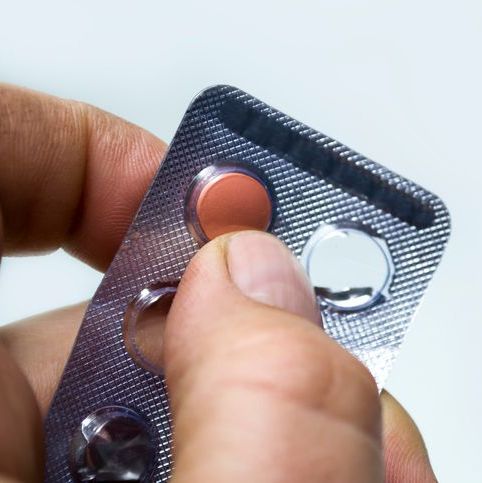 Fingers hold the blister to open the pill for oral administration