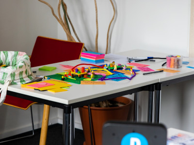 A table filled with post-its, legos and pens. It's a prototype in progress.