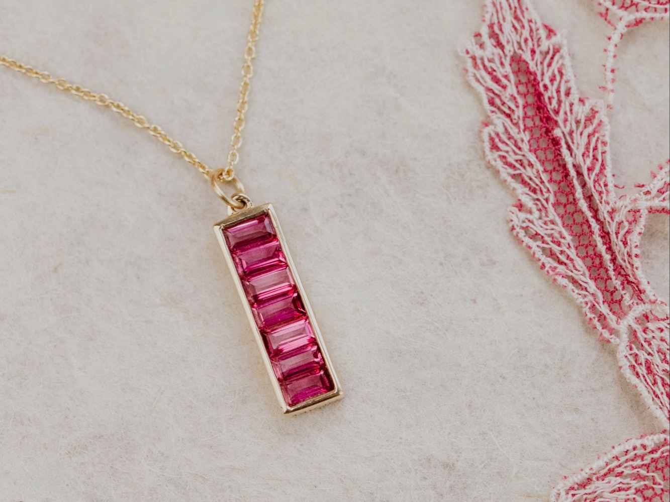Pink Topaz Baguettes in Rectangle Bezel Necklace on a white marbled surface.
