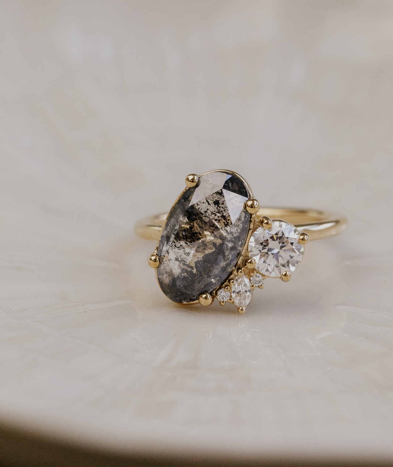 A oval galaxy diamond toi et moi engagement ring on a white surface.