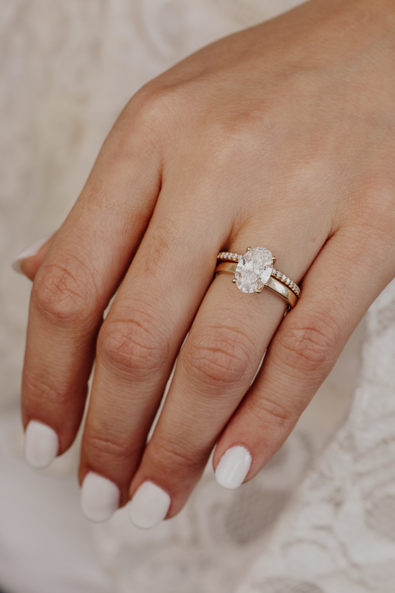 The Octavia oval diamond engagement ring paired with the Jenna diamond band on a models hand.