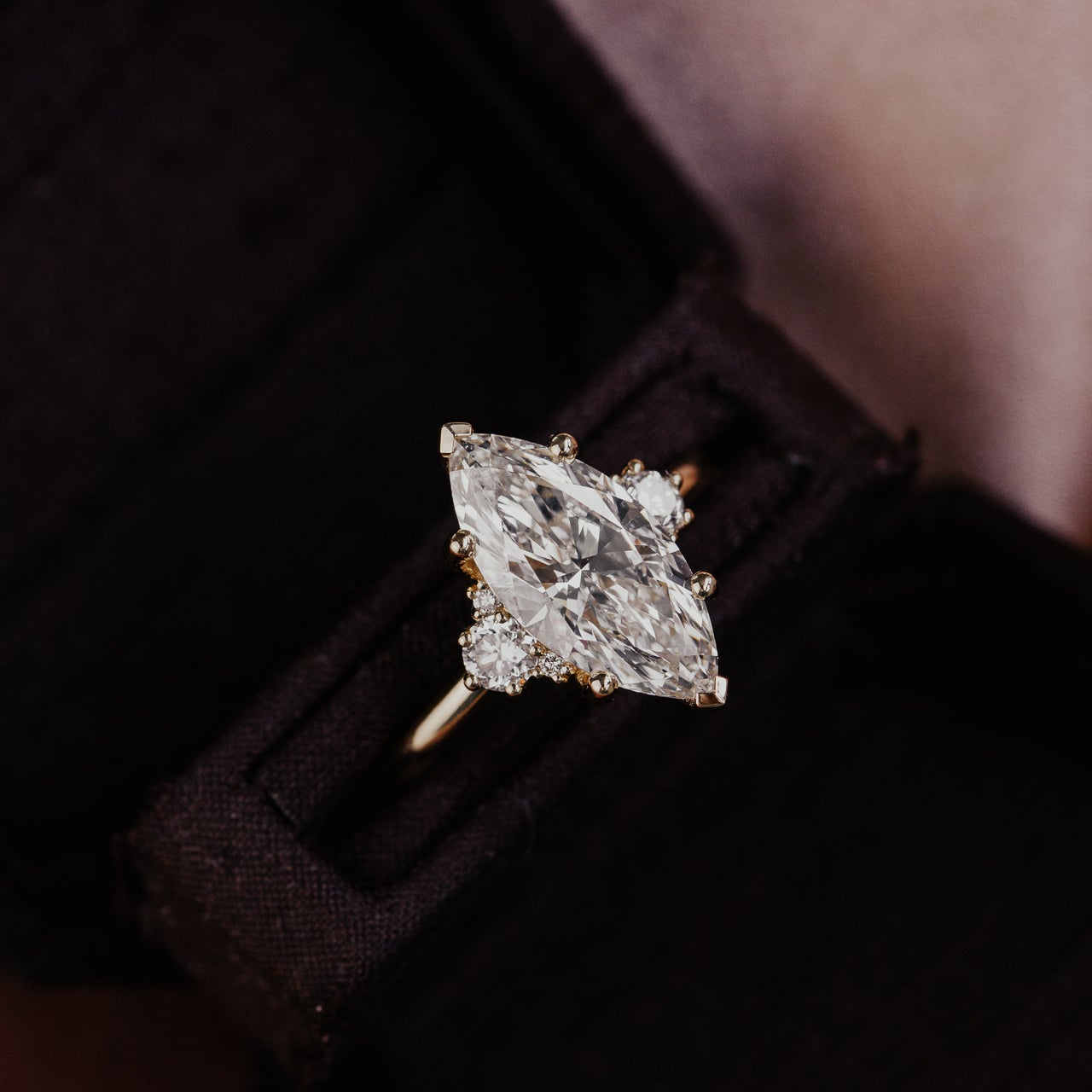 The Vivien marquise diamond engagement ring in a black box with a blurred background.