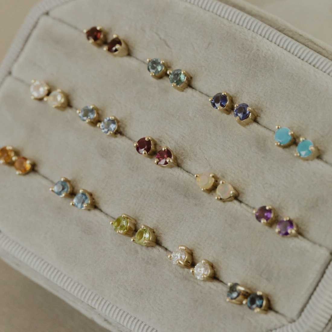 Gemstone stud earrings in multiple gemstones placed in a white jewelry box
