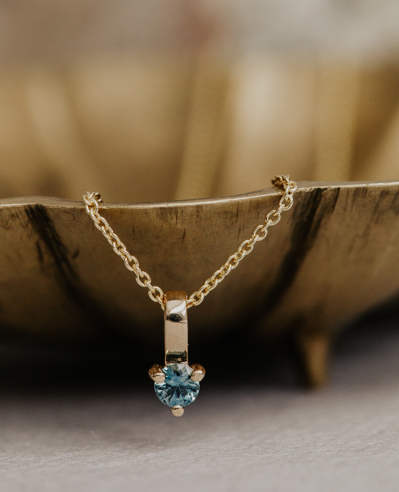 Blue Montana sapphire stackable gemstone charm necklace with a wood background