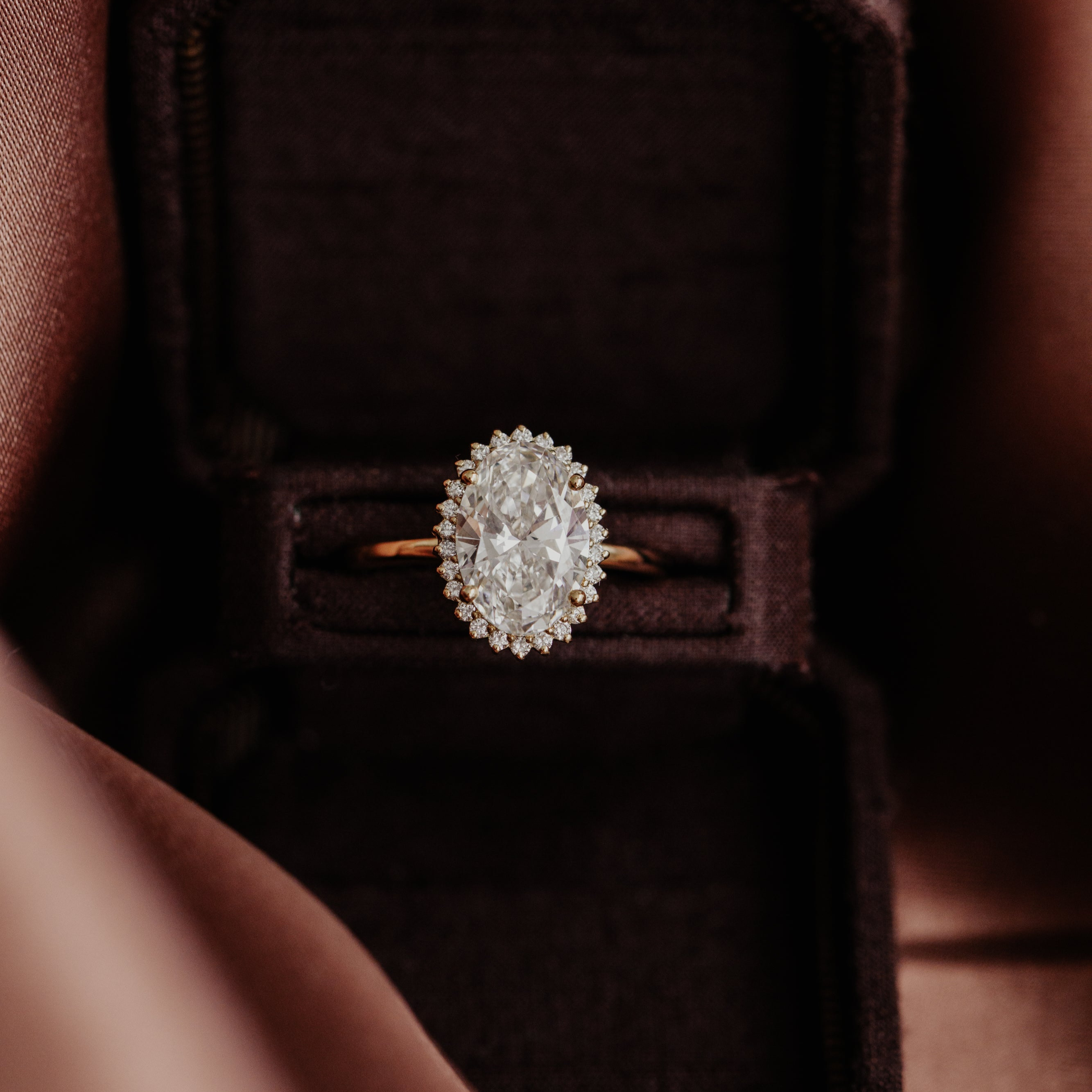 The Nova oval diamond engagement ring in a brown velvet box.