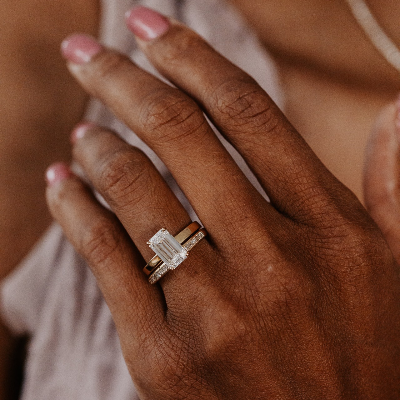 The Octavia Emerald Cut diamond ring stacked with the Alice Baguette and Round Band on a models hand.