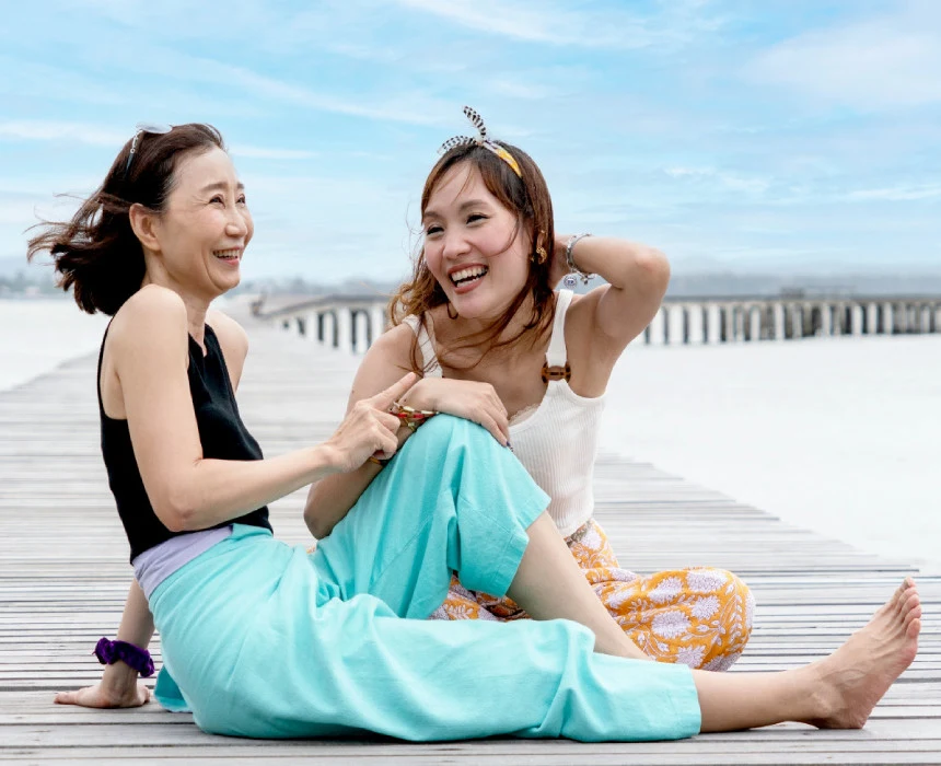 Duas mulheres sentadas e sorrindo na praia