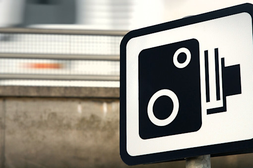 Speed camera sign and blurred truck