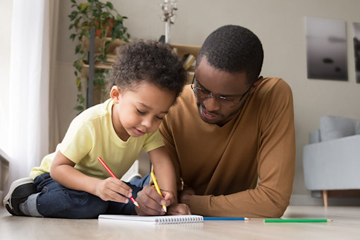 Father and son colouring on the floor