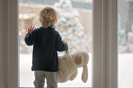 Toddler looking out window at snow