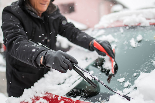 Old man scraping snow off his car window
