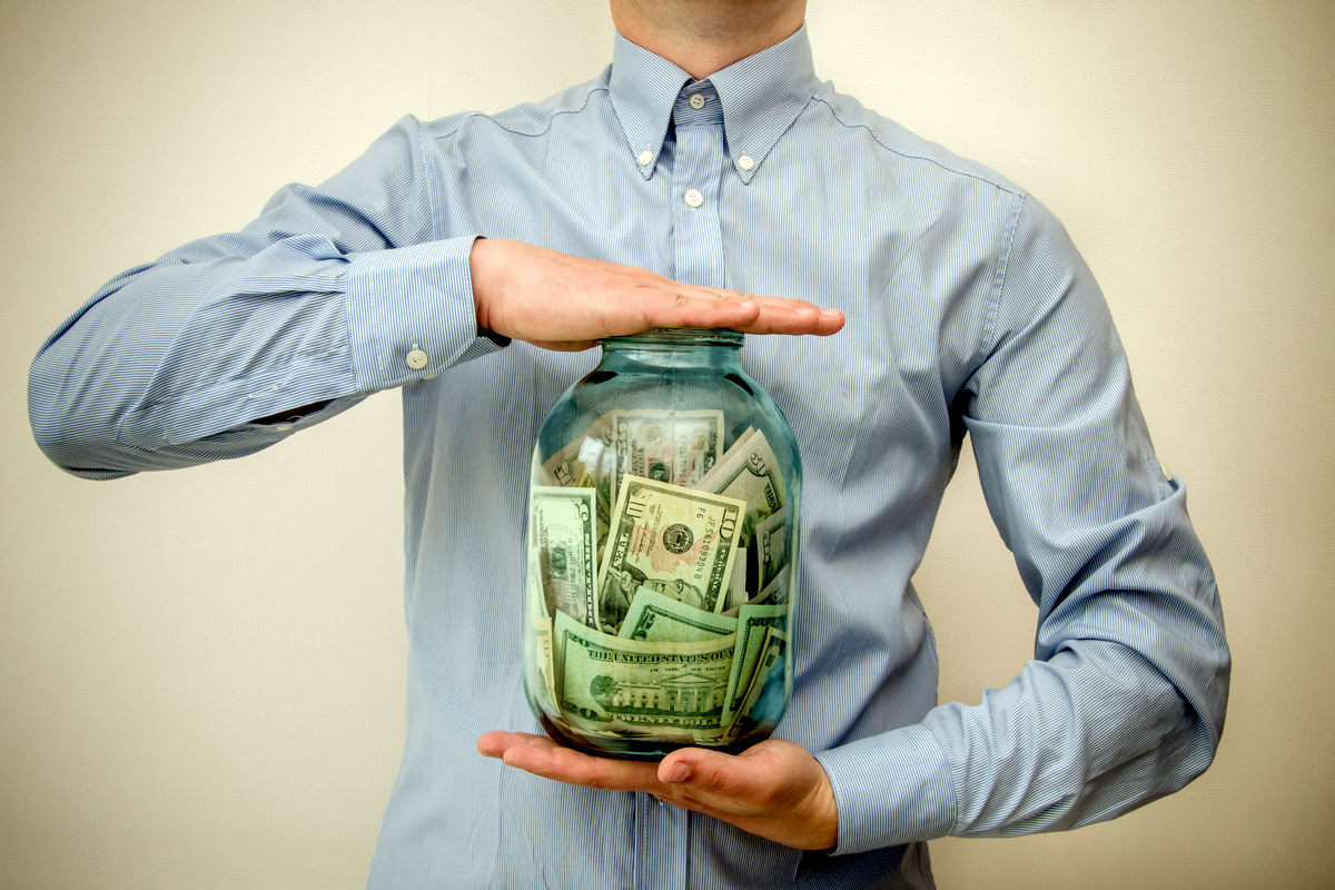 man holding a jar full of money