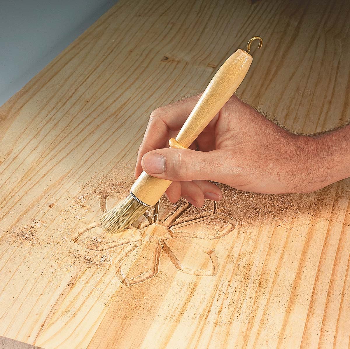 A horsehair detail brush being used to remove dust from relief carving