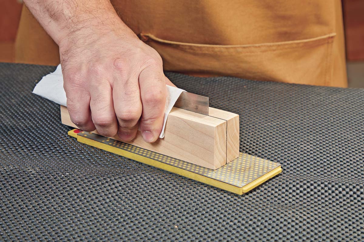 wiping edge of card scraper with cloth