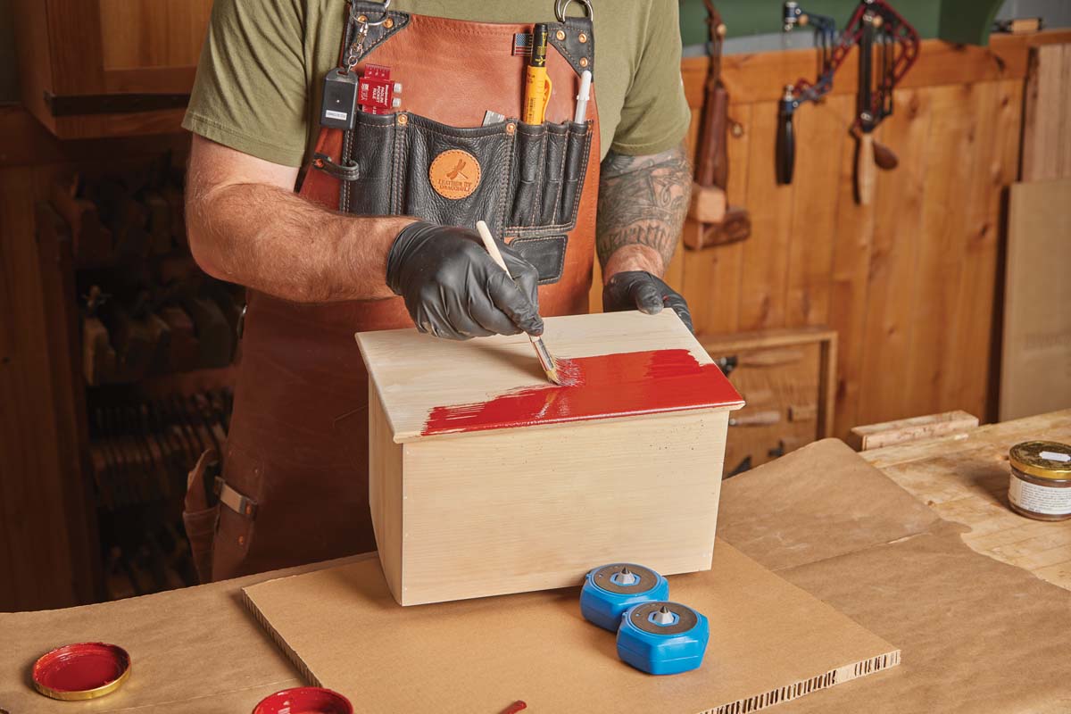 brushing red linseed oil paint on wood box