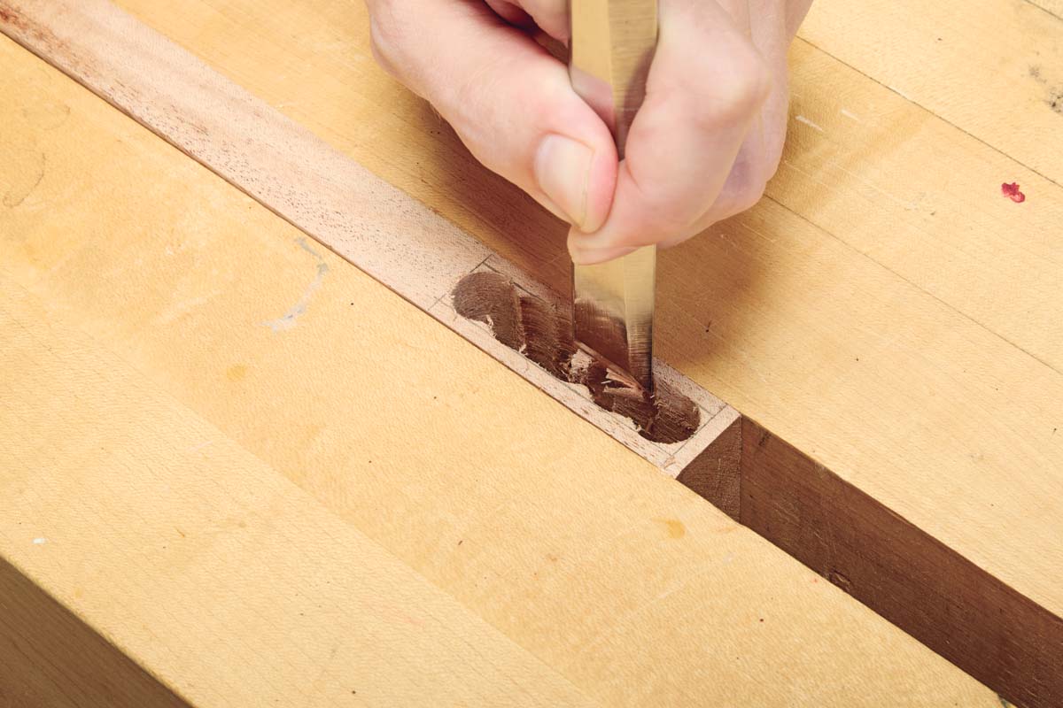 using hand chisel to shape the holes into one rectangle hole