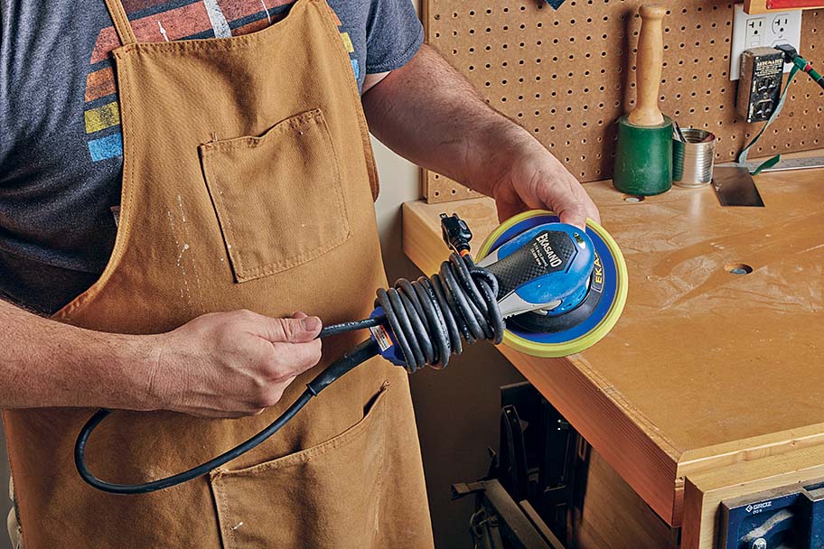 tugging opposite end of cord loop to tighten wrapped cord around orbital sander