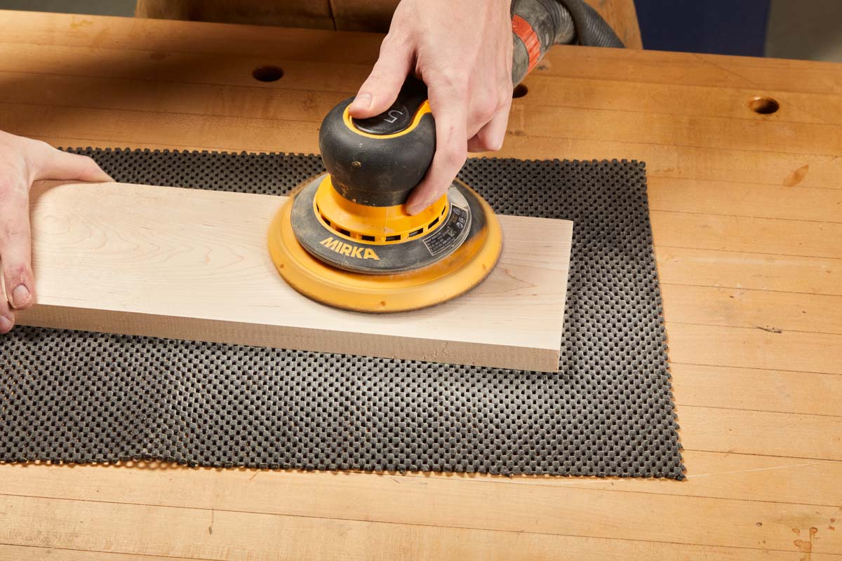 routing piece of wood over routing pad on workbench