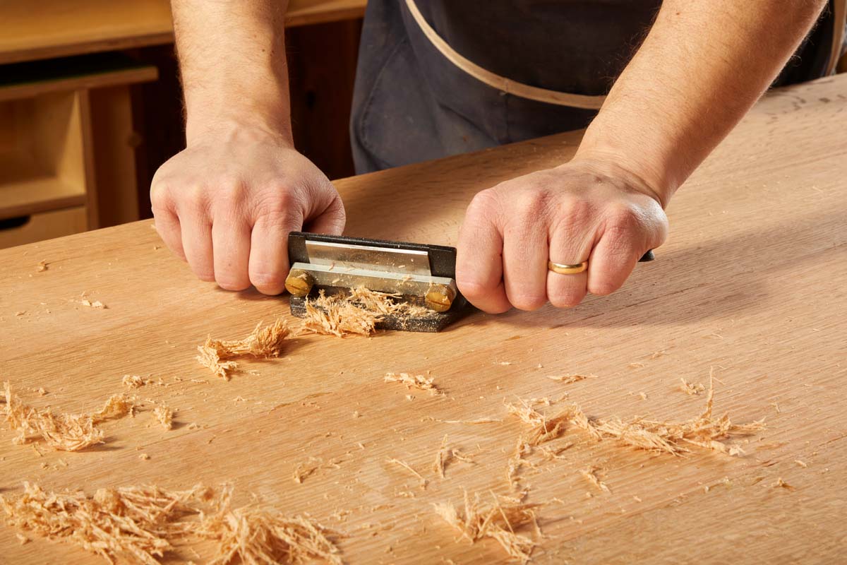 cabinet scraper smoothing wood table surface