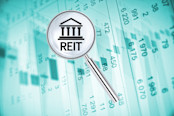 Magnifying lens over background with building icon and text REIT