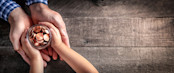 Hands Of Father Giving Jar Of Coins To Child