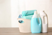 Basket with clean towels and detergents on table.