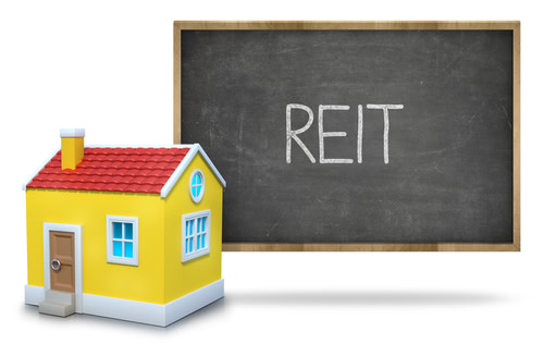 Reit written on blackboard with toy house