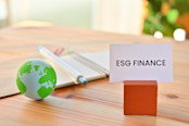 On the desk there is a ball of earth and a card with ESG FINANCE written on it