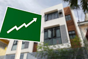 A sign showing an upward arrow in front of an apartment building