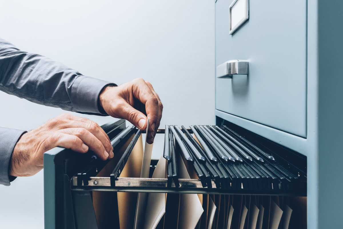 Office clerk searching for files into a filing cabinet drawer