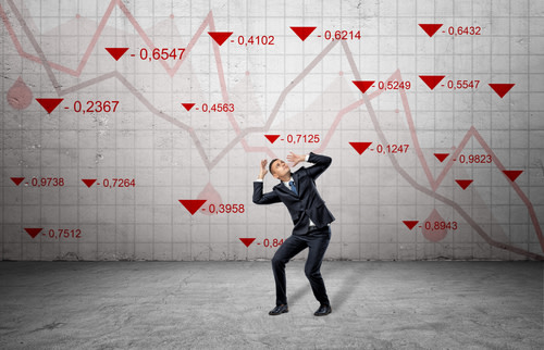 Frightened business man surrounded by red stock market indexes