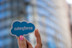 A hand holding up the Salesforce logo.