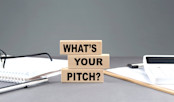What-s Your Pitch text on a wooden block with notebook