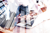 Double exposure image of hands over a laptop and buildings