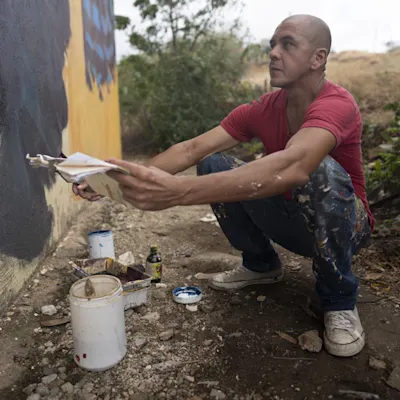 Garrick squatting to paint a wall