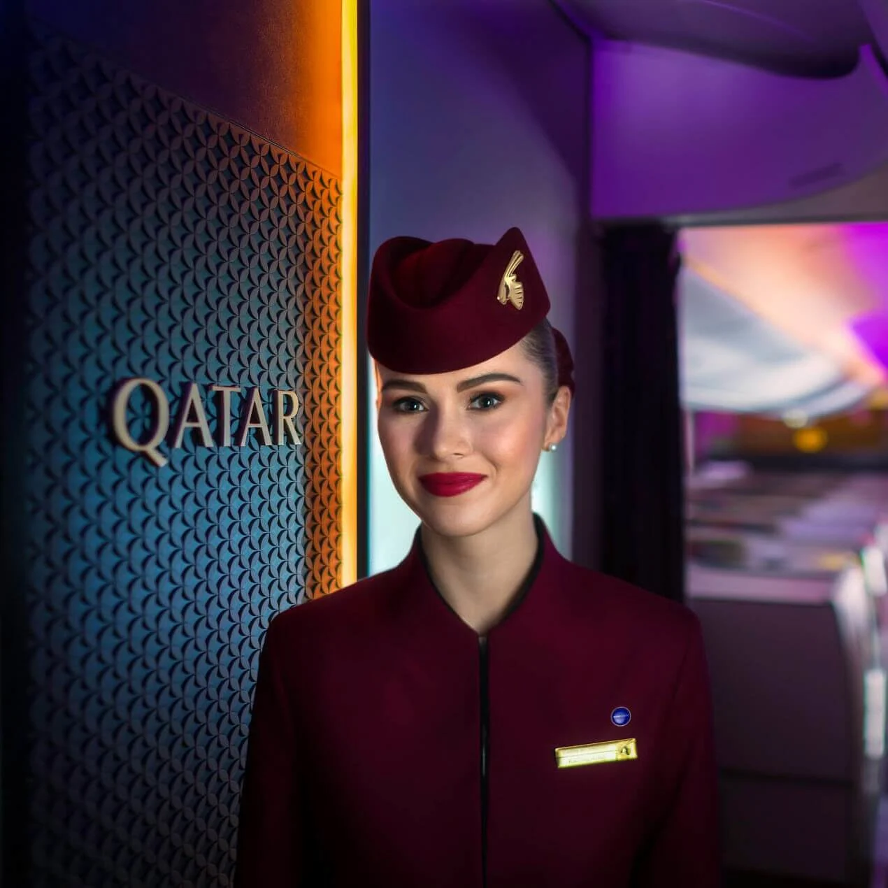 Un agent de bord de Qatar Airways regarde la caméra en souriant.