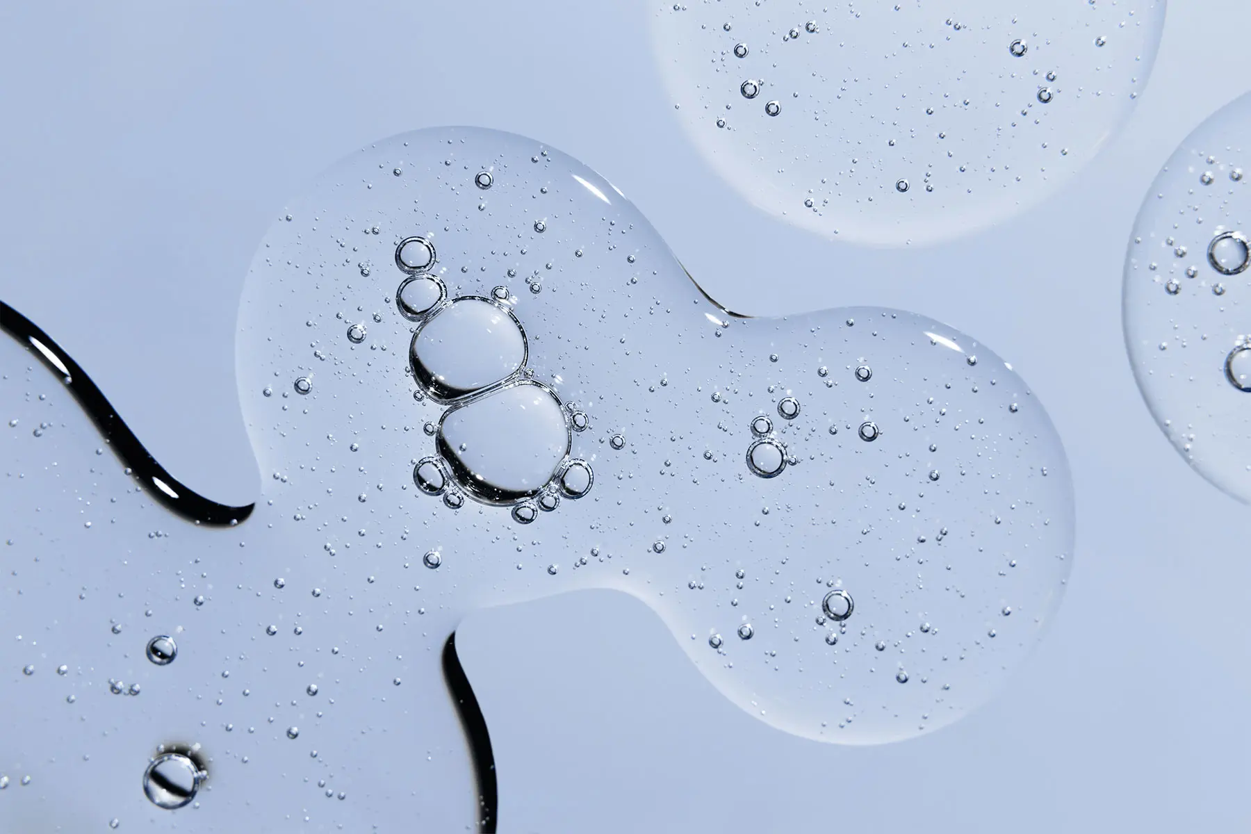 Serum containing peptides in organic pooled shapes on blue background. header
