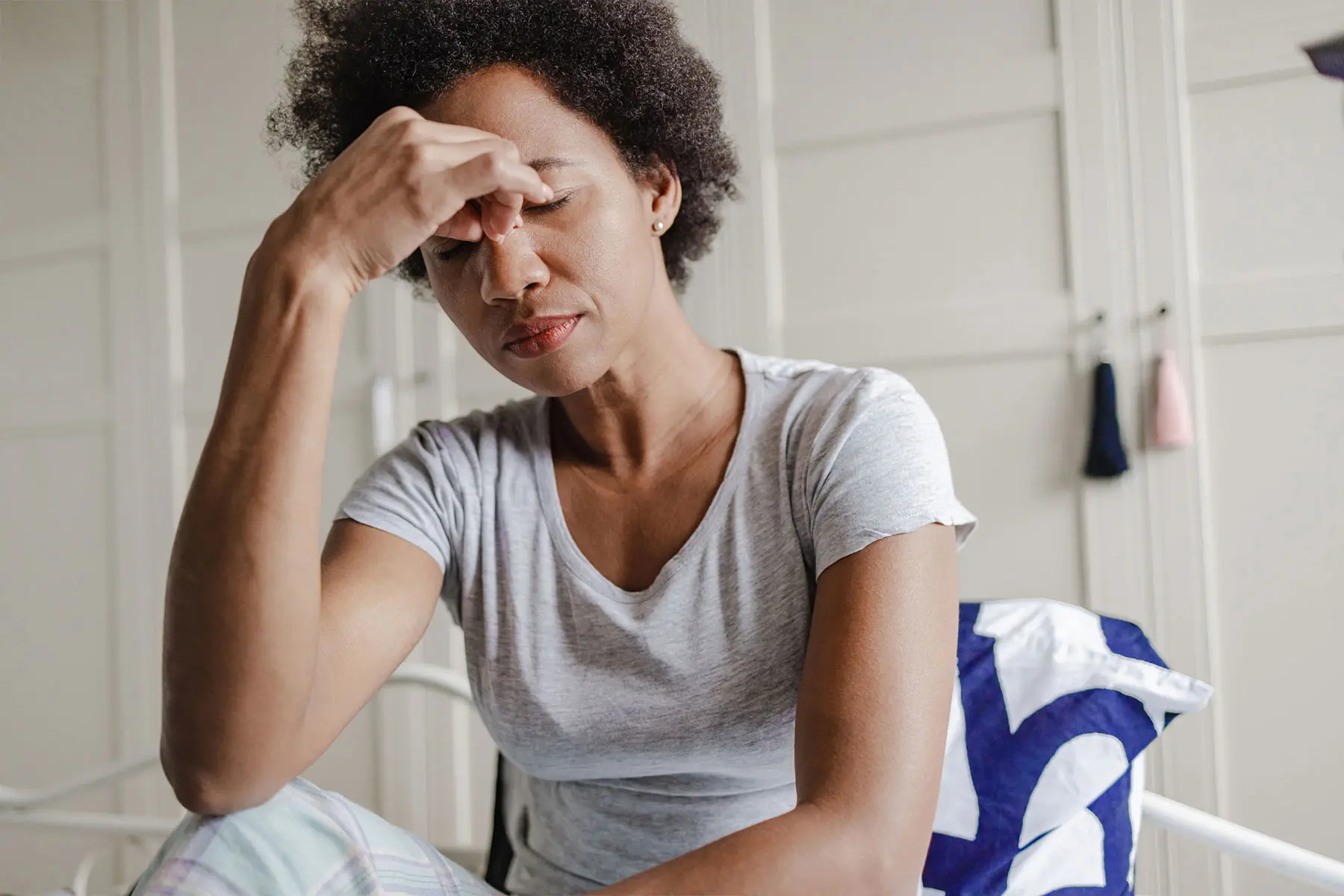 Middle-aged biracial woman with her hand to her forehead in the morning, suffering from headache.