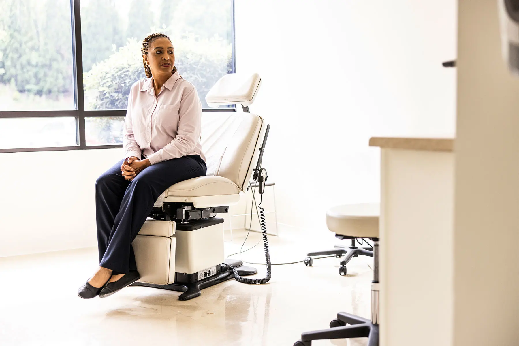 Woman dressed in street clothes in anticipation on a medical chair for a doctor consultation.