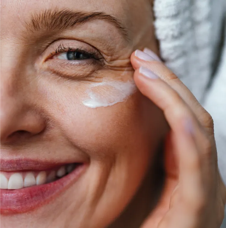 Woman smiling putting on eye cream