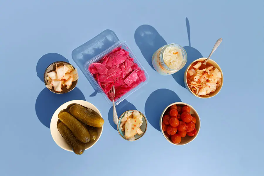 Homemade kimchee, pickled cucumbers, tomatoes, cabbage with beets and sauerkraut on the blue background (inline)