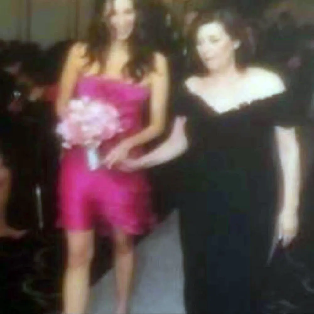 Vintage photo of Randi Friedman and her mother walking down the aisle holding hands with flowers.