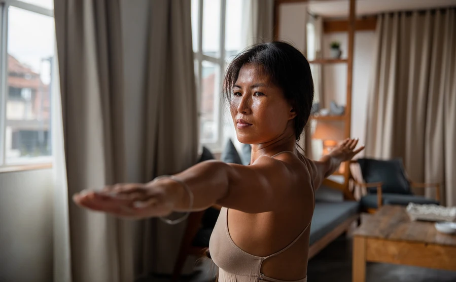 Chinese woman in warrior pose doing yoga in her home. AW289