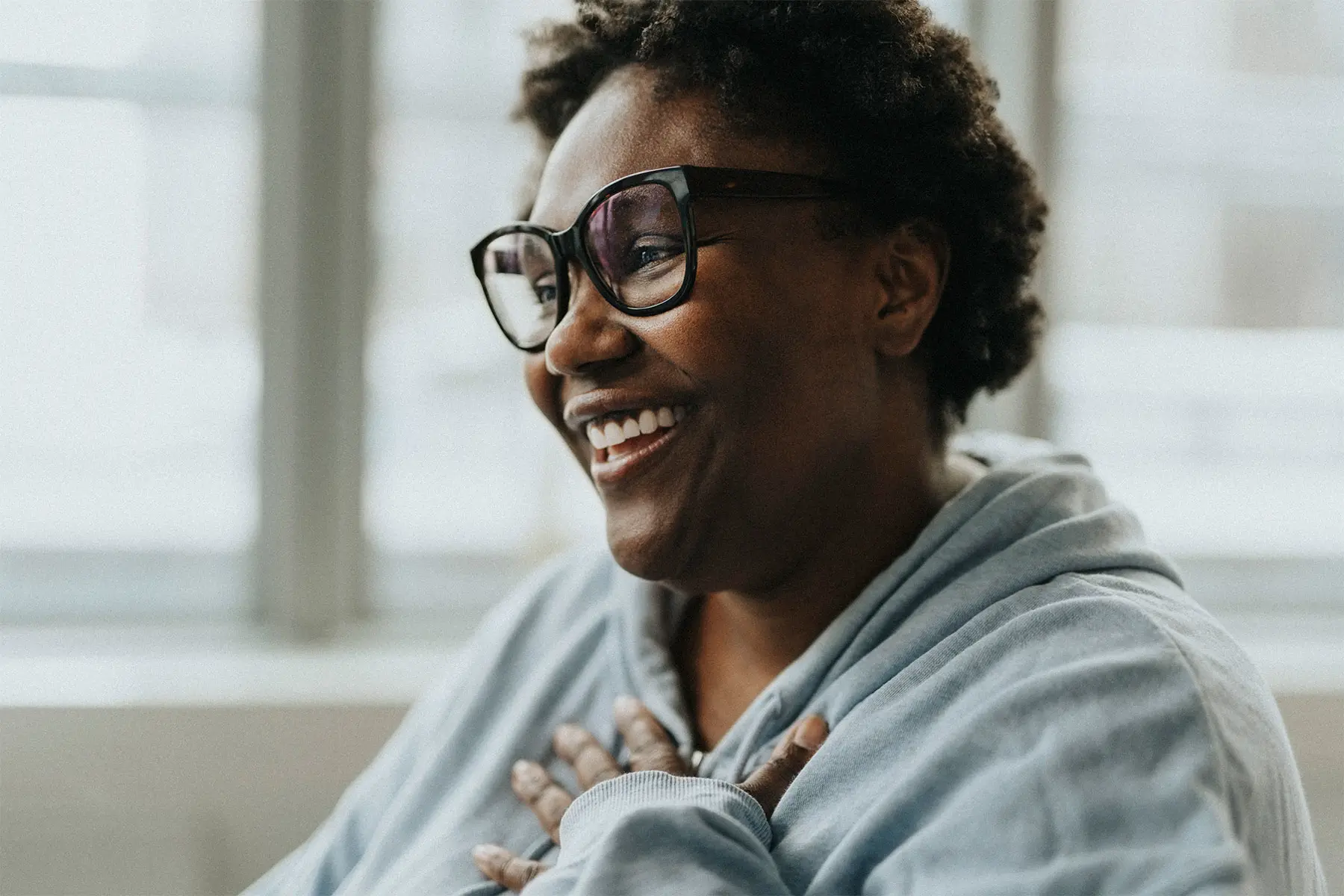 Black woman wearing bold framed eyeglasses gesturing relief while meeting with a physician. header
