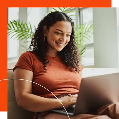 Woman smiling at laptop with orange background