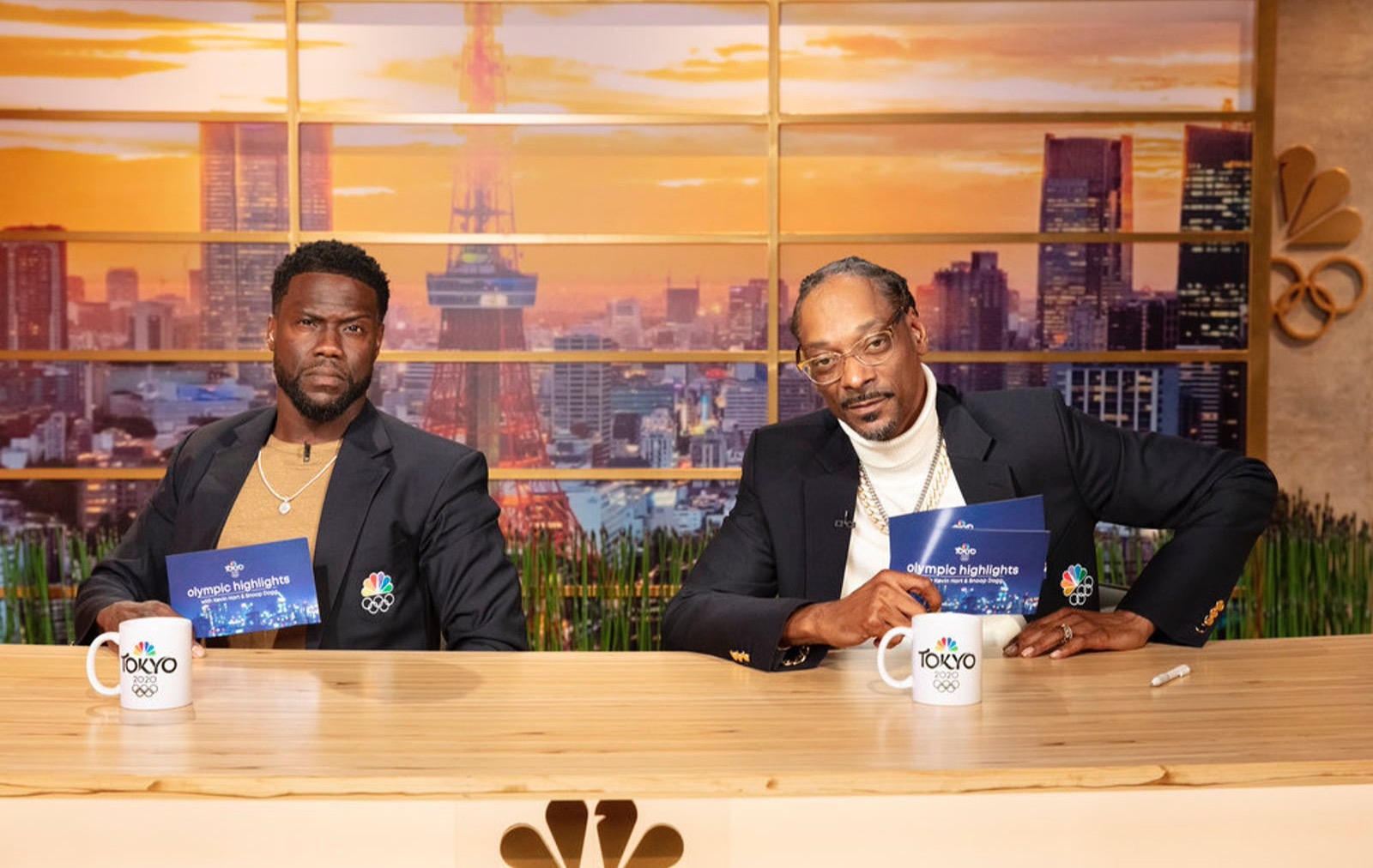 Kevin Hart and Snoop Dogg sitting at NBC Olympics news desk