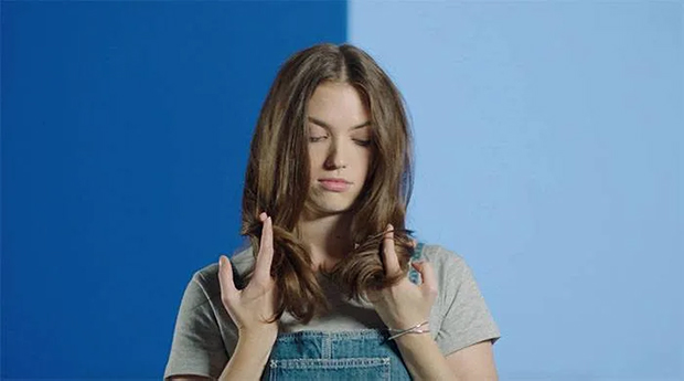 Girl with sad face touching and looking at her dry hair ends