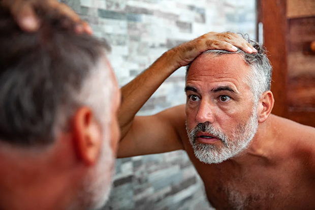 Older men looking at beard in mirror